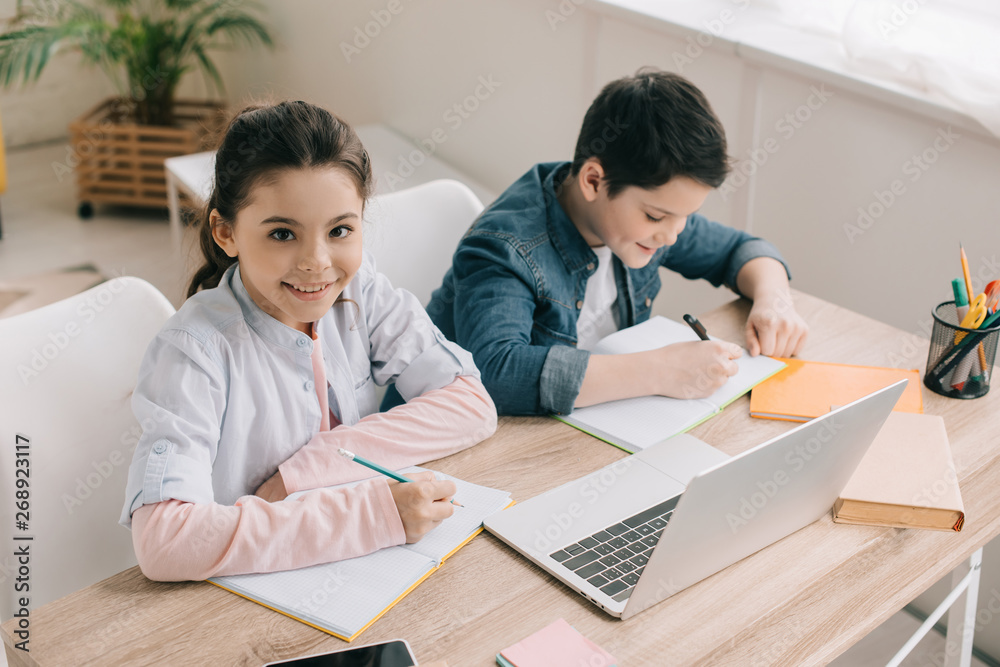 high angle view of cute brother and sister sitting at desk and doing homework together high angle view of cute brother and sister sitting at desk and doing homework together