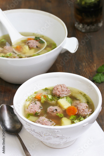 soup with meatballs in a white bowl. light soup with pork meatballs.