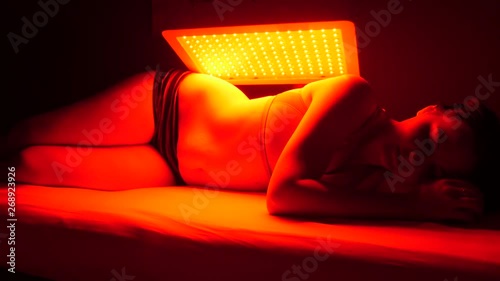 Camera pans from right to left as patient lies on side with the infrared lamp on her back photo