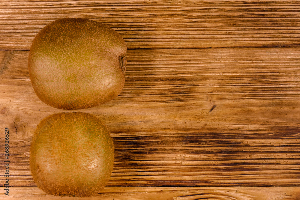 Two kiwi fruits on a wooden table. Top view