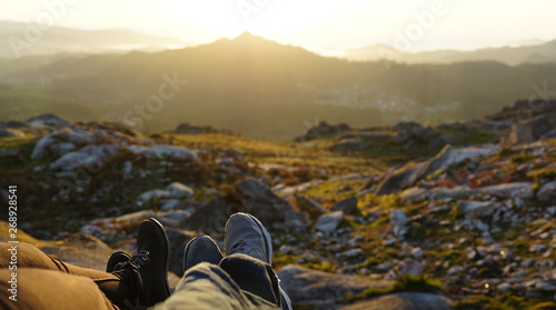 Panoramic detail of two pair of feet in front of a defocused landscape at sunset