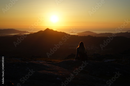 Young woman contemplating the sunset from Mount Galiñeiro in Vigo, Galicia, Spain