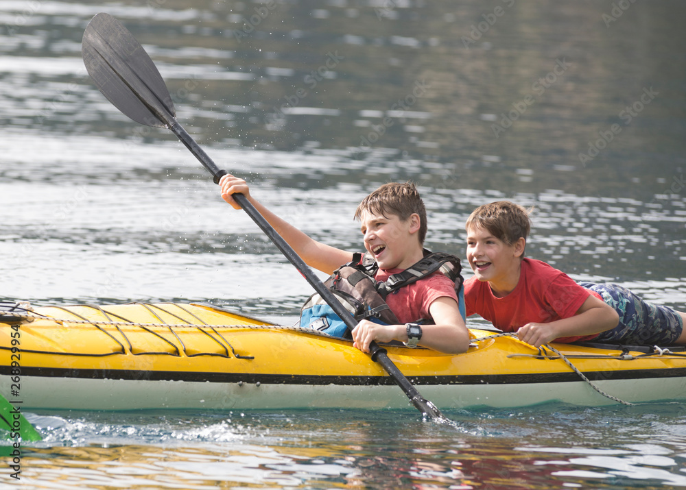 Obraz premium Brothers and friends enjoying their summer vacation in a kayak
