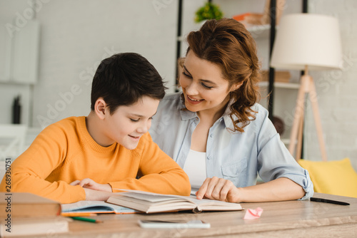Tableau sur toile smiling mother helping adorable son doing schoolwork at home