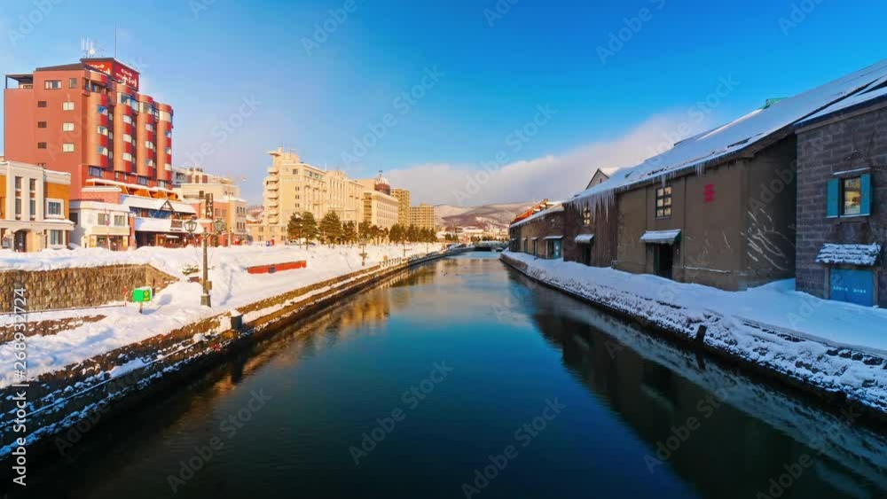 Daytime beauty after a winter snowfall of the Otaru Canal in Hokkaido, Japan, a popular skiing destination. Traffic passing on a street and wind blowing across the surface of calm water. Daytime beauty after a winter snowfall of the Otaru Canal in Hokkaido, Japan, a popular skiing destination. Traffic passing on a street and wind blowing across the surface of calm water.