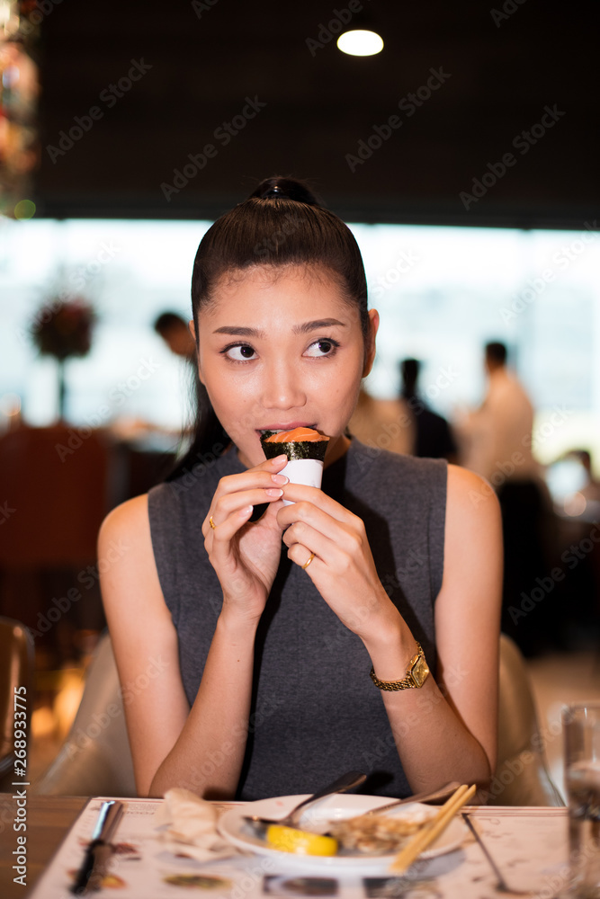 Working Asian Woman Black hair having Lunch one bite sushi Dinner of  Western food in fusion restaurant cafe and eat alone. Concept enjoy eating  myself for good food life Stock Photo |