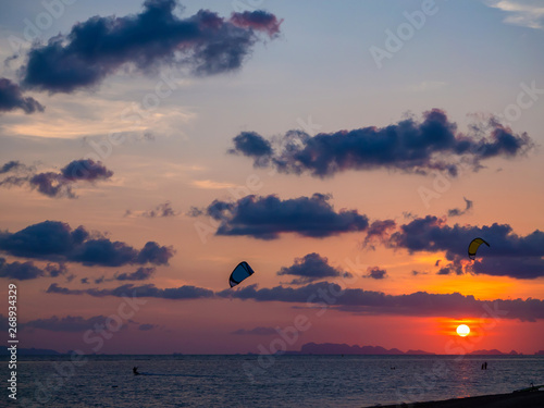 Silhouette people kitesurfing sunset clouds. Koh Phangan. Thailand