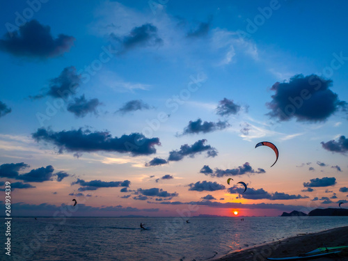 Silhouette people kitesurfing sunset clouds. Koh Phangan. Thailand