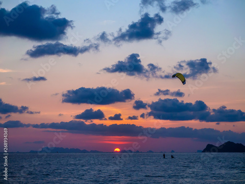 Silhouette people kitesurfing sunset clouds. Koh Phangan. Thailand