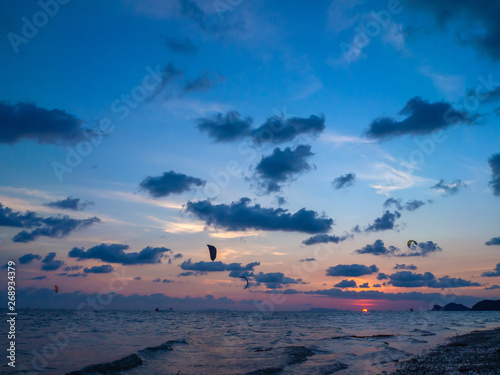 Silhouette people kitesurfing sunset clouds. Koh Phangan. Thailand