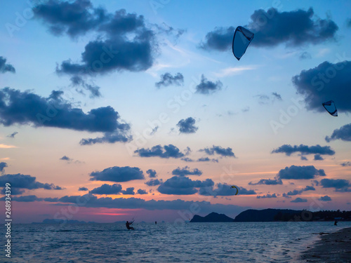 Silhouette people kitesurfing sunset clouds. Koh Phangan. Thailand