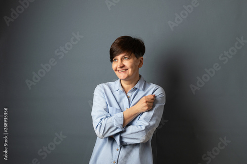 Middle-aged woman posing standing near the wall. Woman portrait on a gray background. Copy space.