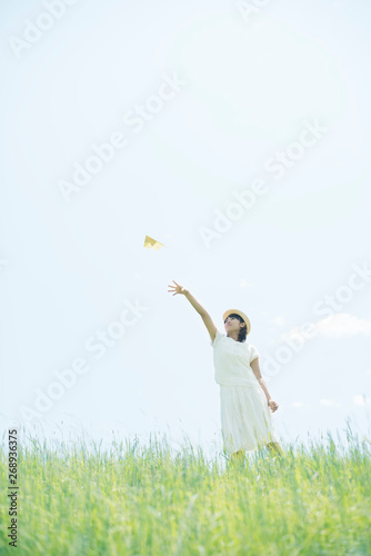 草原で紙飛行機を飛ばす女性