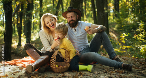 Snack time. Happy family with kid boy relaxing while hiking in forest. Basket picnic healthy food snacks fruits. Mother father and small son picnic. Picnic in nature. Vacation and tourism concept