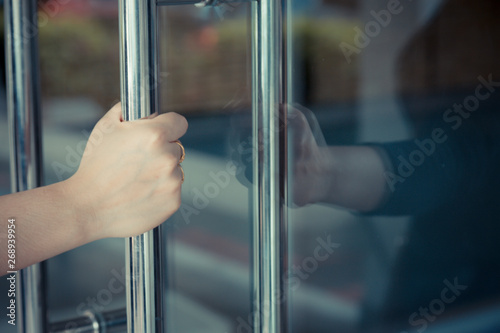 Woman's hand open the door with glass reflection