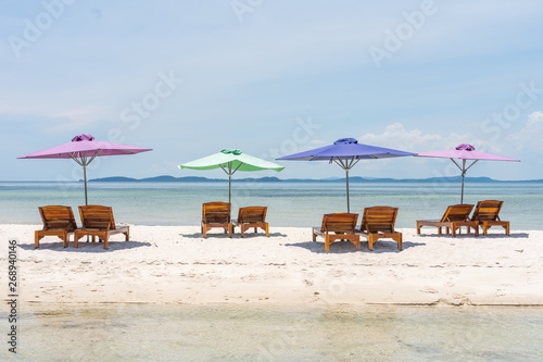 Fototapeta Naklejka Na Ścianę i Meble -  Four lounge chairs and umbrella at the white sand beach