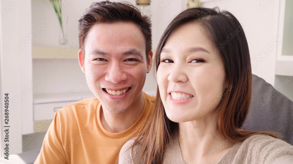 Asian couple using smartphone VIDEO Call with friend in living room at home, sweet couple enjoy love moment while lying on the sofa when relaxed at home. Lifestyle couple relax at home concept. Asian couple using smartphone VIDEO Call with friend in living room at home, sweet couple enjoy love moment while lying on the sofa when relaxed at home. Lifestyle couple relax at home concept.