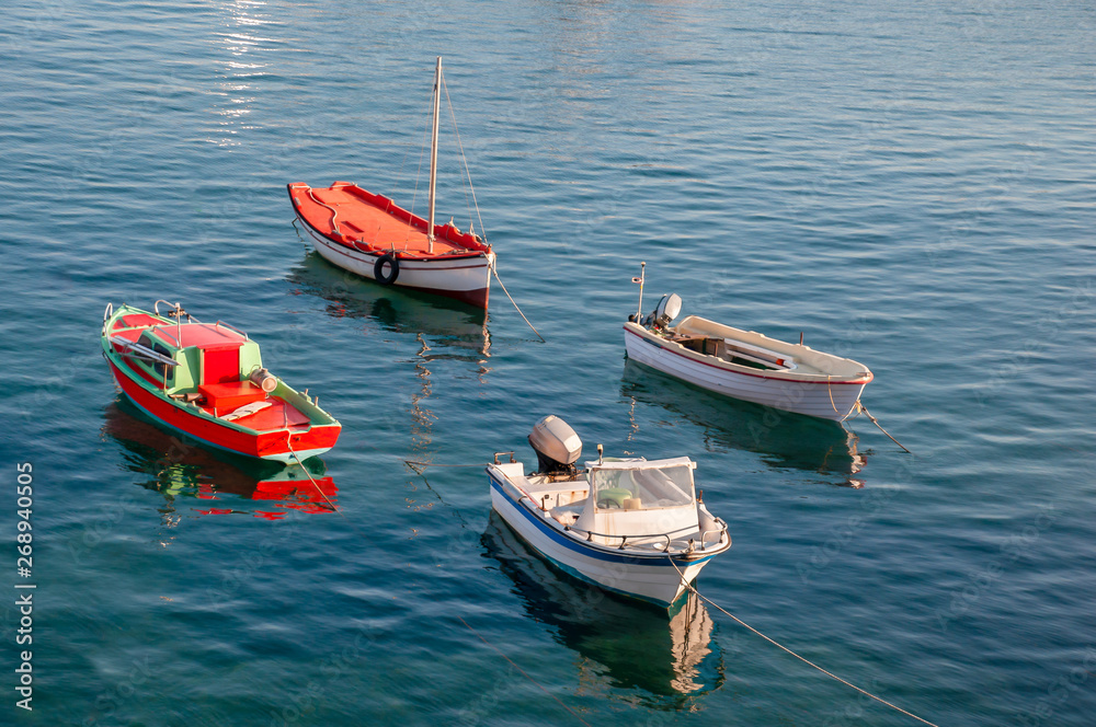 Four different fishing boats anchored in a bay Four different fishing boats anchored in a bay