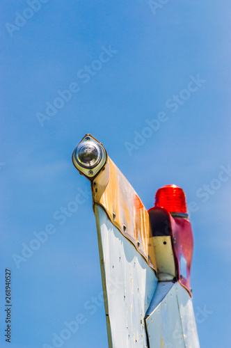 Tail fin, rudder and beacon lights, small single engine airplane with old paint and bright blue sky.