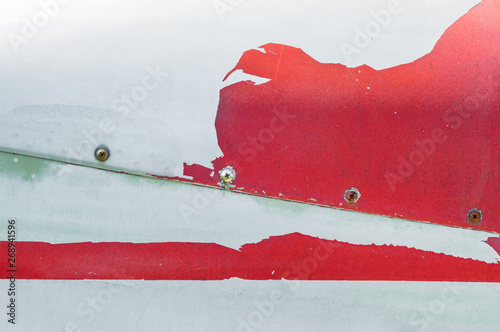 Old peeling red paint on metal surface of airplace fuselage. photo