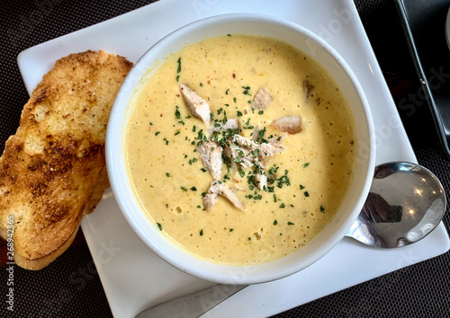 Corn soup in the white cup with garlic bread on the wooden table