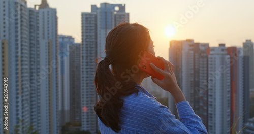 Photography Woman talk to cellphone in the background of the city under sunset time