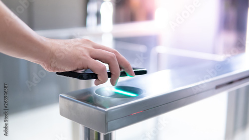 Male hand using smartphone to open automatic gate machine in office building photo