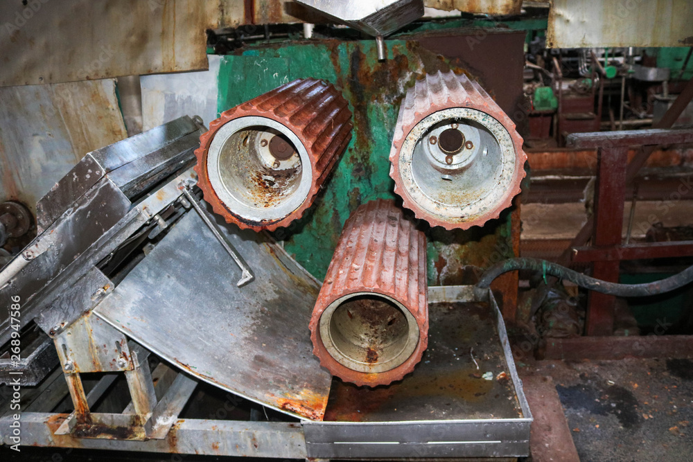 Large metal rollers rolls with teeth of the gears of the production line, a conveyor belt in the workshop at an industrial chemical petrochemical machine-building refinery with equipment machines