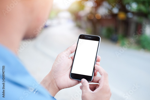 Cropped shot view of man hands holding smart phone with blank copy space screen for your text message or information content, female reading text message on cell telephone during in urban setting. © wattana