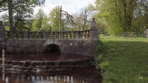 Characterful ornate bridge in country walk in Fife Scotland with small stream under cascading into pond photo