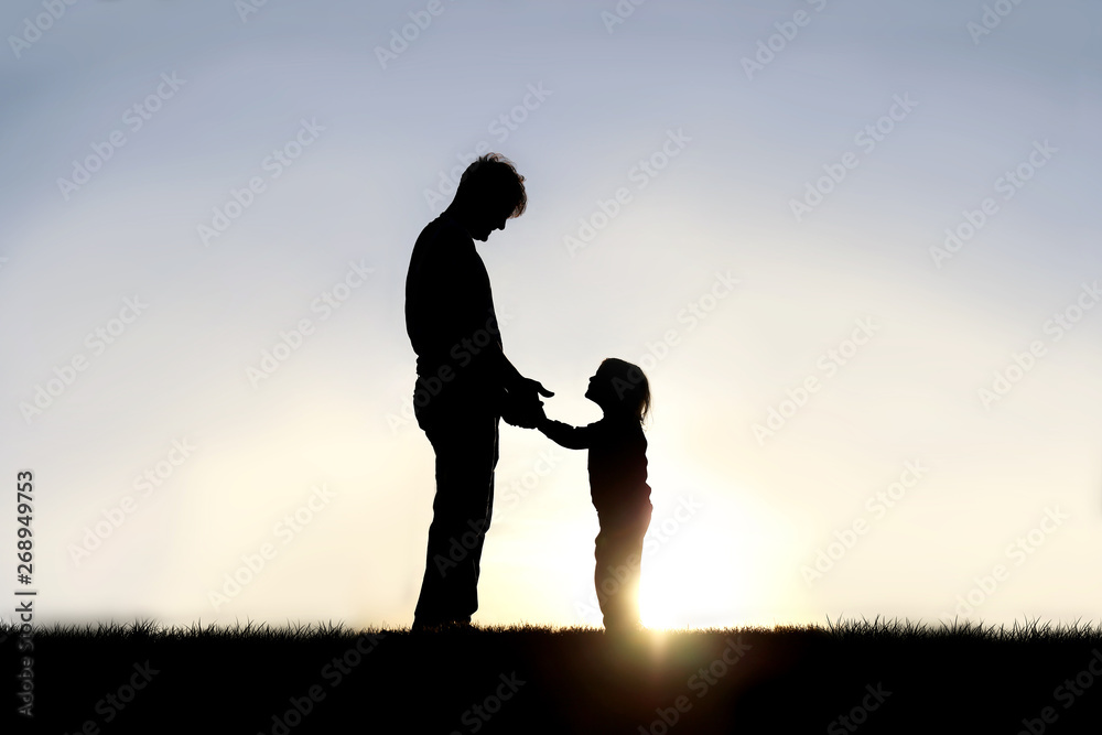 Silhouette of Father and his Happy Little Child Holding Hands and Smiling at Eachother Outside