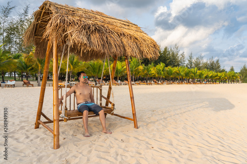 Asian man relax on the swing at the beach