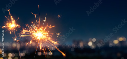 Burning sparkler with blurred bokeh cities light background photo