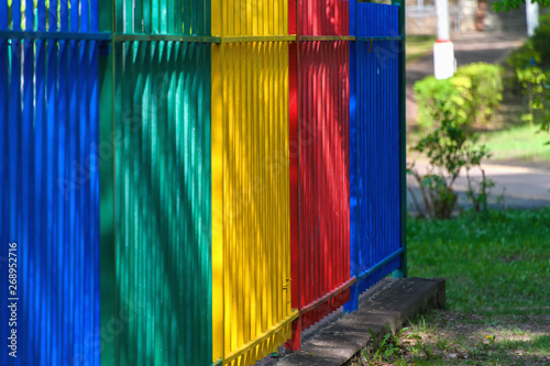 Multi-colored metal fence in the park around the children's rides.