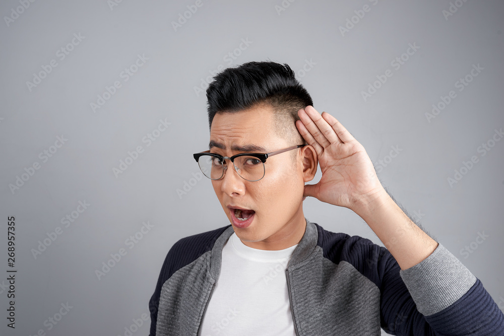Portrait of young casual man which overhears conversation over white background Portrait of young casual man which overhears conversation over white background