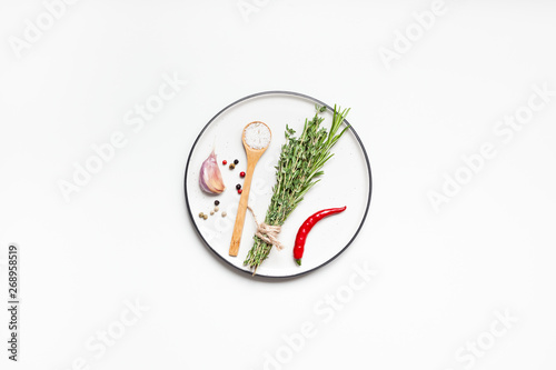 Fototapeta Naklejka Na Ścianę i Meble -  Empty plate with greens herbs and spices around