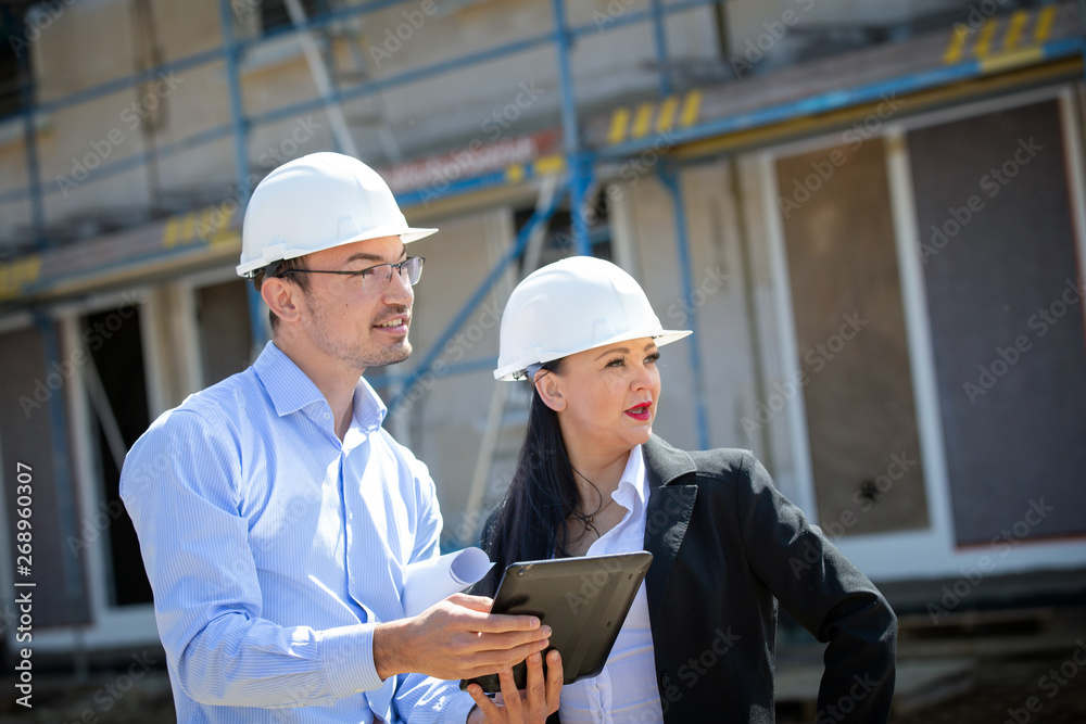 Two architects a man and a woman in construction in white helmets. Two architects a man and a woman in construction in white helmets.