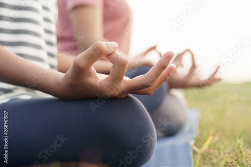 close up hand and half body of health woman sit in lotus yoga position in the morning at park. Practicing yoga makes meditation for healthy breathing and relaxation