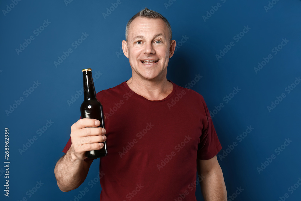 Happy middle-aged man with bottle of beer on color background Happy middle-aged man with bottle of beer on color background
