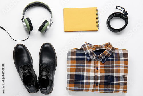 Stylish male clothes with headphones and notebook on white background