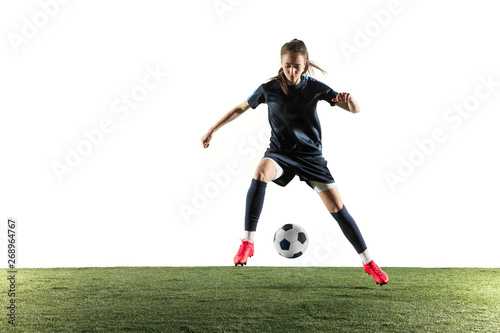 Young female football or soccer player with long hair in sportwear and boots kicking ball for the goal in jump isolated on white background. Concept of healthy lifestyle, professional sport, hobby. © master1305