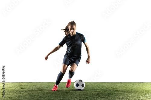 Young female football or soccer player with long hair in sportwear and boots kicking ball for the goal in jump isolated on white background. Concept of healthy lifestyle, professional sport, hobby. © master1305