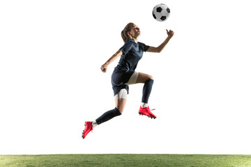 Young female football or soccer player with long hair in sportwear and boots kicking ball for the goal in jump isolated on white background. Concept of healthy lifestyle, professional sport, hobby.