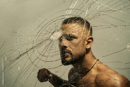 Determination to succeed. Muscular man having inner determination and commitment to break glass wall. Determined latino man removing obstacle with determination and confidence. Determination concept photo