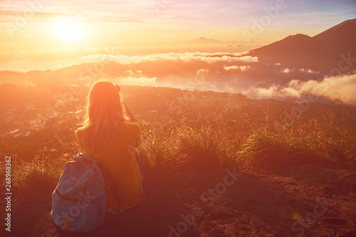 Woman enjoying nice landscape and sunrise from a top of mountain Batur, Bali, Indonesia.