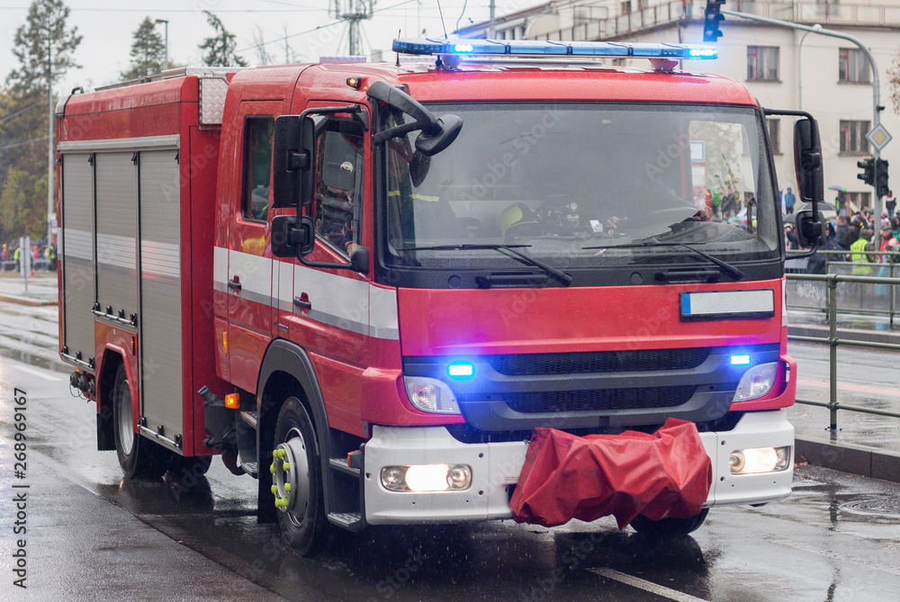 Obraz premium Pracownicy straży pożarnej jadą wozem strażackim na defiladzie wojskowej