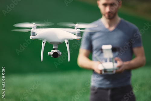 Young man piloting a drone on a spring field