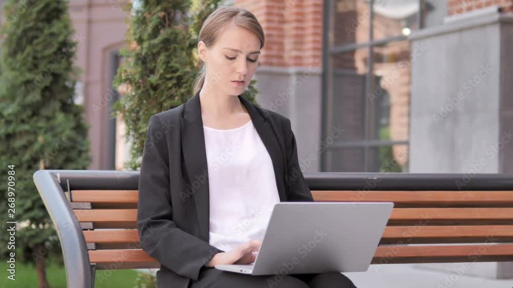 Young Businesswoman working on Laptop, Sitting Outdoor on Bench