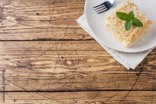 Layered cake with cream Napoleon millefeuille vanilla slice with mint on wooden background. photo