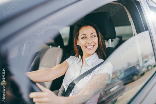 Gorgeous smiling Caucasian brunette driving her car.